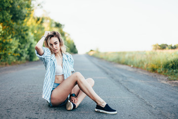 Beautiful girl hitchhiking on the track in a man's shirt