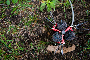 tourist gas burner of red color on the ground with green grass in natural conditions ready to use