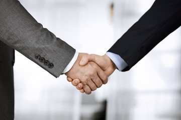 Business people in office suits standing and shaking hands, close-up. Business communication concept. Handshake and marketing