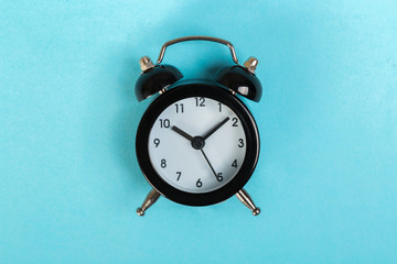 black vintage alarm clock on a colored background, top view. concept of time, daily routine