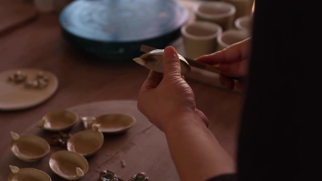 Female potter sands her works.