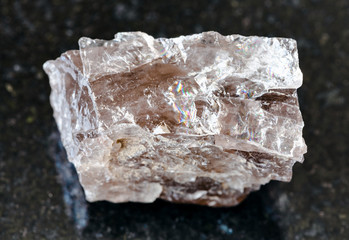 closeup of sample of natural mineral from geological collection - rough Smoky Quartz rock on black...
