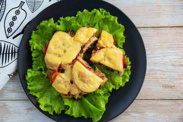 Chicken fillet with mushrooms, beans and tomatoes under cheese on a salad leaf