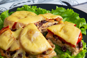 Chicken fillet with mushrooms, beans and tomatoes under cheese on a salad leaf