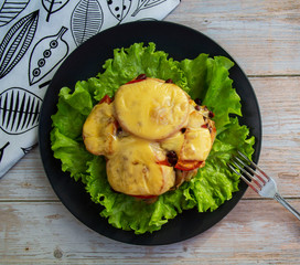Chicken fillet with mushrooms, beans and tomatoes under cheese on a salad leaf