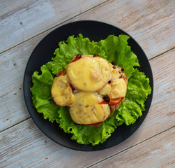 Chicken fillet with mushrooms, beans and tomatoes under cheese on a salad leaf