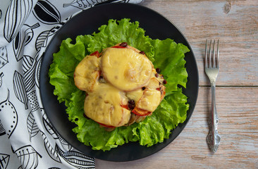 Chicken fillet with mushrooms, beans and tomatoes under cheese on a salad leaf