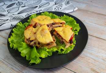 Chicken fillet with mushrooms, beans and tomatoes under cheese on a salad leaf