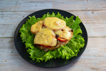 Chicken fillet with mushrooms, beans and tomatoes under cheese on a salad leaf