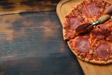 testy pizza with salami tomato sauce cheese with slice in piece on a wooden table background