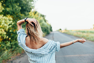 Beautiful girl hitchhiking on the track in a man's shirt