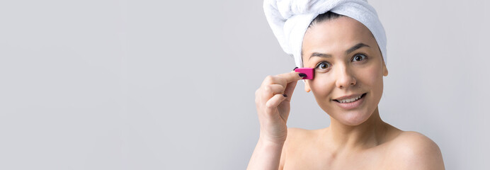 Beauty portrait of woman in white towel on head with a sponge for a body in view of a pink heart. Skincare cleansing eco organic cosmetic spa relax concept.