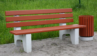Park bench with an urn for rubbish made of concrete and wood.