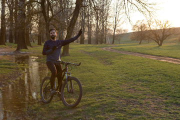 Cyclist in shorts and jersey on a modern carbon hardtail bike with an air suspension fork standing on a cliff against the background of fresh green spring forest