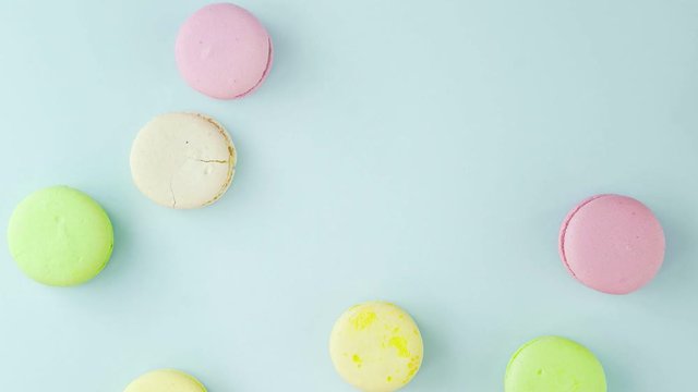 Macaroons or macaron on pastel blue surface with coffee in red cup.