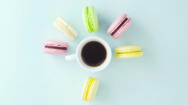 Macaroons or macaron on pastel blue surface with espresso in white cup.