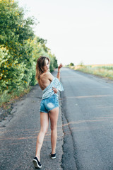 Beautiful girl hitchhiking on the track in a man's shirt