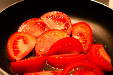 Fresh chopped tomato is fried in a pan in sunflower oil.