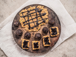 bird view of healthy vegan peanut butter granola bars and balls with oats, cacao, marble syrup, dates and cashew nuts on a wooden board on a table