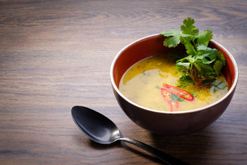 Tom Yum Kung soup in a bowl on wooden table background. Traditional thai asian spicy coconut milk soup with chicken, seafood and vegetables. Restaurant menu. Close up, copy space