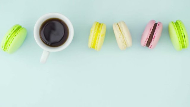 Macaroons or macaron on pastel blue surface with espresso in white cup.