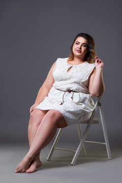Plus size fashion model in casual clothes, fat woman on gray background