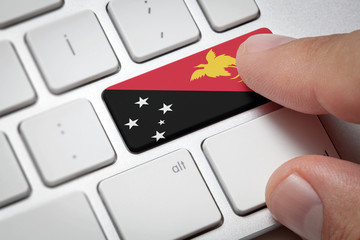 Online International Business concept: Computer key with the Papua New Guinea on it. Male hand pressing computer key with Papua New Guinea flag.