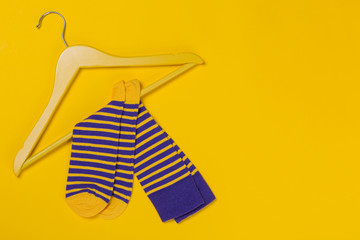 pair of blue yellow striped socks on a yellow wooden hanger, shopping and discounts concept