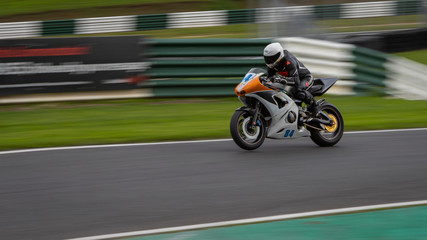 A panning shot of a white racing bike speeding round a racetrack.	