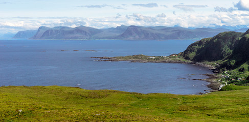 View from Runde bird island in Alesund, Norway towards little fishing village, the ocean and the mountains in the background.