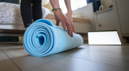 Fototapeta na wymiar woman rolling yoga mat at home empty laptop screen