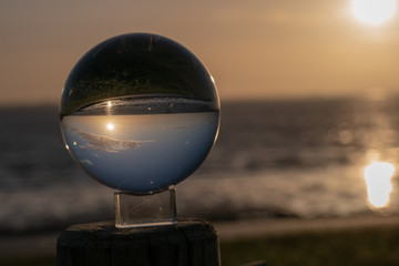 Fototapeta na wymiar Sunset over the sea seen through a glasball