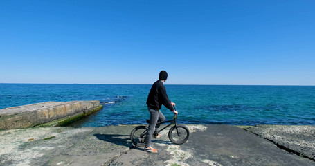 Young male with bmx bicycle ride near the sea