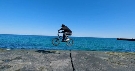 Young male with bmx bicycle ride near the sea