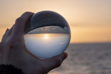 Fototapeta na wymiar Sunset over the sea seen through a glasball