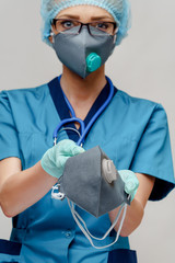 female doctor with stethoscope wearing protective mask and latex gloves over light grey background