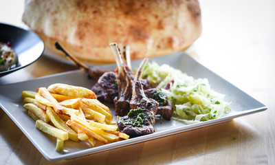 delicious grilled lamb chopsticks with french fries, pesto sauce & mix of lettuces