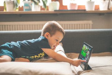 Young Child Boy Watching Cartoon on Tablet in the Couch