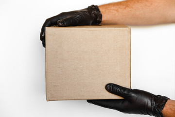 courier man on black rubber gloves keep brown cardboard box package on white backgrond