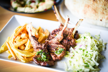 delicious grilled lamb chopsticks with french fries, pesto sauce & mix of lettuces