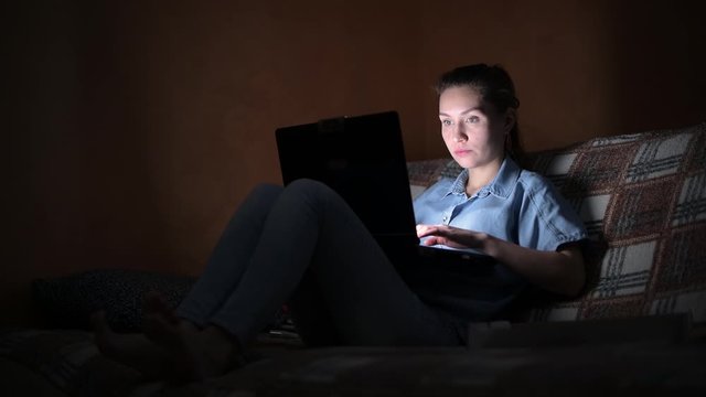 Working on a laptop with food. girl works at the computer late at home and eats pizza in a dark room.