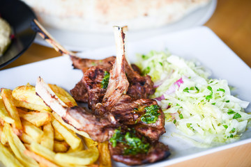 delicious grilled lamb chopsticks with french fries, pesto sauce & mix of lettuces