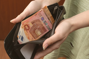 The presence of money in the wallet. Female hands holding a wallet with cash