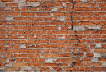Naklejka premium Wall of old brick with broken plaster
