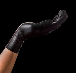 Hand in black glove holding something isolated on black background