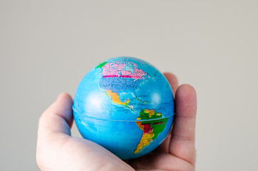 Close-up   of  miniature globe held in hand with the map of America  .
