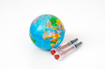 Two  syringes near  a   miniature    earth  globe representing the concept of research and finding the covid-19 vaccine .