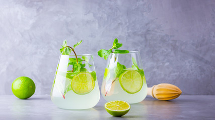 Cocktail mojito with lime and mint in glass. Two glasses of mojito on a gray background