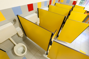 bathroom of school with small yellow doors and tiny toilets