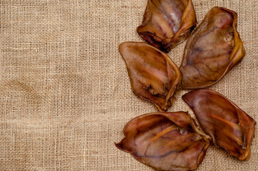 Five dried pork ears on burlap.